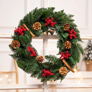 Classic Christmas wreath with red berries, pine cones and cinnamon on white wooden window