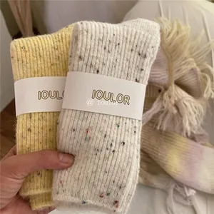 Detail of ruffled crew socks in yellow and cream knit with colorful speckled textures