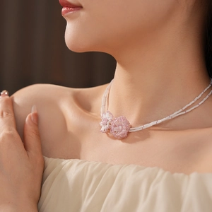 Close-up of a double-layered beaded necklace with pink flowers worn by a model