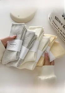 Close-up of three pairs of vertical ribbed knit cotton socks in beige and soft gray tones