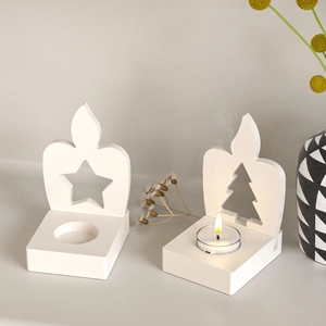 Detail of star and tree cutouts on white plaster candle holder mold with tea light lit