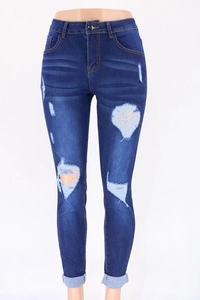 Close-up of ripped details and rolled cuffs on dark blue high-waist denim jeans