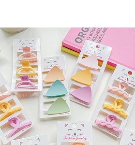Detailed view of matte pastel hair clips in pink and yellow on brand display cards