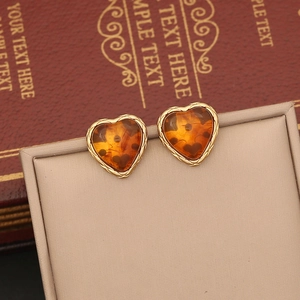 Vintage amber heart earrings with gold textured frames displayed on an elegant stand
