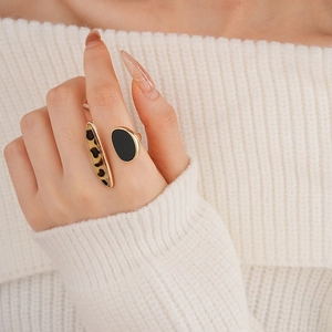 Close-up of golden open ring with leopard print and black enamel on finger