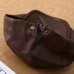 Detail of dark brown leather beret with lychee grain and vintage bronze buckle