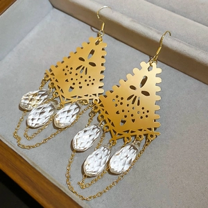 Detailed close-up of gold geometric earrings with sparkling teardrop crystal tassels