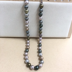 Detailed view of Morandi-colored Tahitian style pearl necklace on white display board