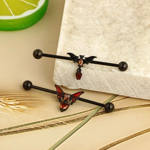 Macro detail of gothic bat industrial barbells with red gems and coffin pendants
