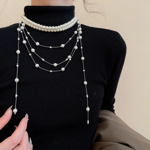 Detail of multi-layer pearl necklace with silver tassels on black sweater