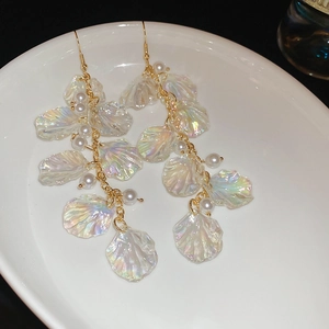Macro detail of iridescent shell tassel earrings with pearls and gold metal hooks