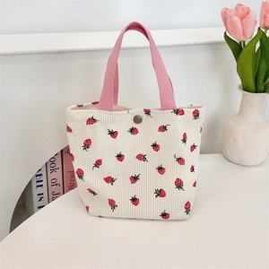 Détails de la texture velours et imprimé fraise sur un sac à bandoulière crème
