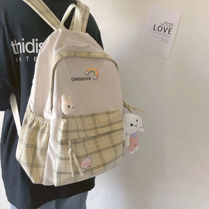 Detail of plaid canvas backpack with rainbow embroidery and cute plush toy pendant