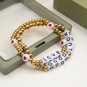 Detail of beaded friendship bracelets with golden beads and LOVE GOOD LUCK letter cubes