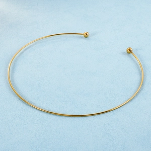Detail of golden C-shape titanium steel collar necklace with round bead ends