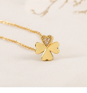 Macro detail of gold clover pendant with three polished petals and one zircon heart petal