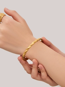 Detailed view of gold twisted rope bangle with alternating matte and polished textures