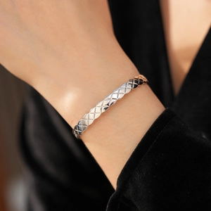 Gros plan d'un bracelet manchette argenté à motif matelassé porté par un mannequin chic
