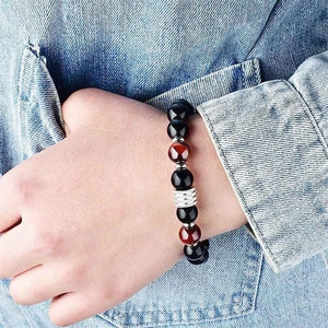 Detailed view of 10mm tiger eye and obsidian beaded bracelet with silver accents on wrist