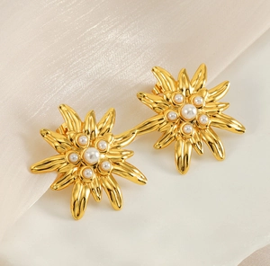 Gros plan de boucles d'oreilles fleurs en or 18 carats avec perles sur marbre blanc