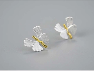 Macro detail of handmade S925 silver butterfly stud earring with gold accents