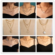 Macro display of gold and silver layered Cuban link necklaces with coin and letter pendants