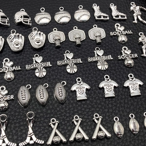 Macro view of assorted silver sports pendants including baseball and football on black background
