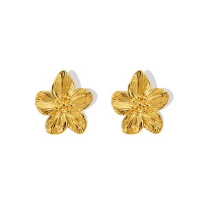 Macro detail of gold flower stud earrings featuring textured petals and center stamens