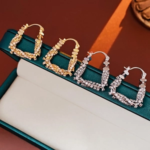 Detailed macro view of U-shaped gold and silver earrings with zircon pavé setting
