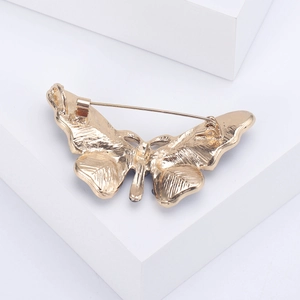 Golden metal butterfly brooch showing the back structure and pin on white background