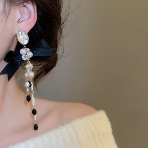 Detail of bowknot earring with pearl tassels and crystal on a model's ear