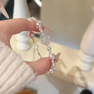 Gros plan du bracelet de perles roses avec fleurs en zircon porté au poignet