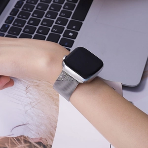 Detail of silver Milanese loop band for Apple Watch on wrist in office setting