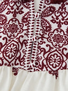 Detail der burgunderfarbenen Druckbluse mit Quasten und geknöpfter Knopfleiste