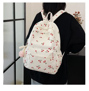 Rear view of model wearing a white corduroy backpack with red cherry print details