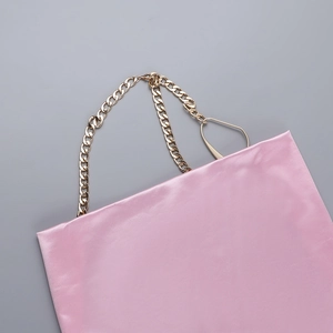 Détail d'une robe en satin rose avec une chaîne dorée et un col bénitier élégant