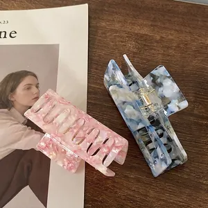 Pink and blue marble texture acetate hair claws with gold springs on wooden desk