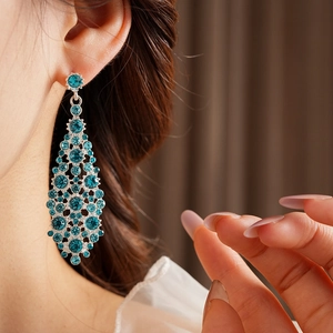 Primer plano de pendientes largos de gota azules con engaste plateado en modelo