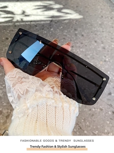 Close-up of oversized rimless sunglasses featuring gradient lenses and silver metal rivets