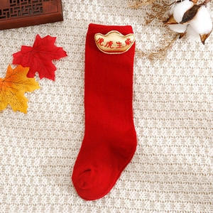 Detailed view of red knitted baby socks with 3D golden ingots and tiger embroidery