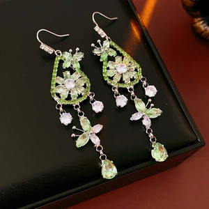 Detail of silver drop earrings with green zircon flower and butterfly pendant in black box