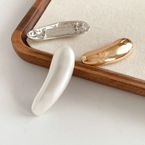 Detailed close-up of metallic bar brooches in gold and silver on a wooden tray