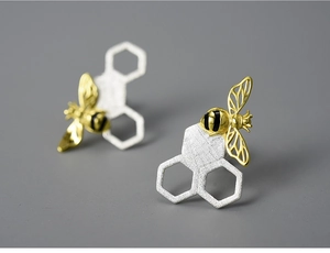Macro shot of silver honeycomb studs with detailed gold bees and black stripes