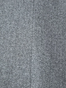 Vista macro del tessuto di lana grigio e della cucitura verticale di un cappotto lungo