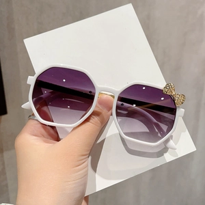 Detail of white polygon frames with purple gradient lenses and gold metal bow decoration