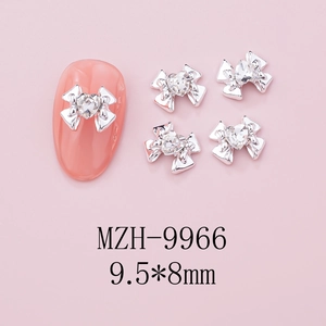 Detailed view of silver bow nail art charm with heart-shaped crystal on pink background