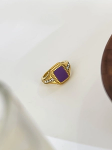 Macro view of gold ring with rectangular purple stone and zircon side accents
