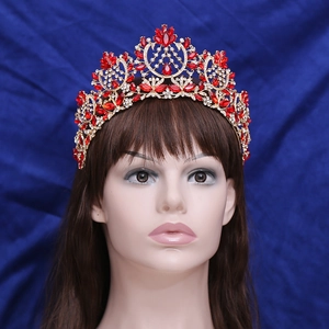 Close-up of golden Baroque crown with red gemstones and crystals on a model