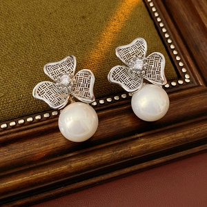Macro detail of vintage floral pearl earrings with zircon stones on green velvet