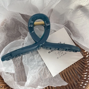Détail d'une grande pince à cheveux bleu foncé dans un panier avec ressort doré